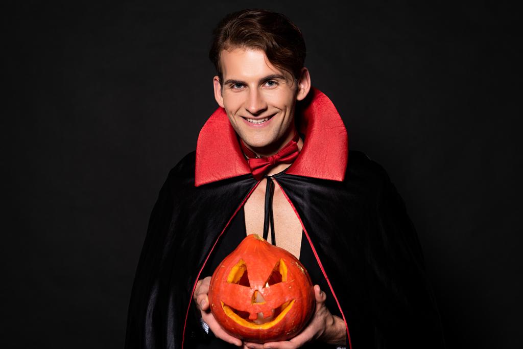 homme heureux tenant citrouille halloween isolé sur noir
  - Photo, image