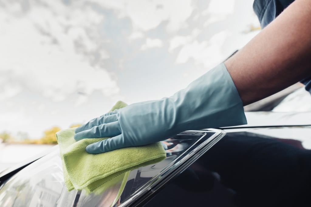 vue recadrée du nettoyeur de voiture dans le gant en caoutchouc essuyant voiture avec chiffon
  - Photo, image