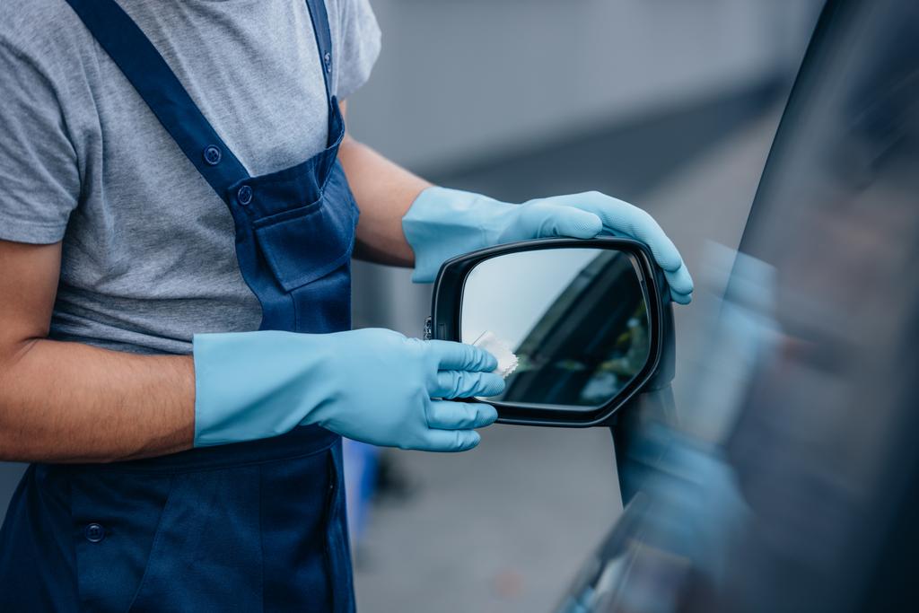 Arabanın yan aynasını silen araba temizleyicisinin kırpılmış görüntüsü - Fotoğraf, Görsel