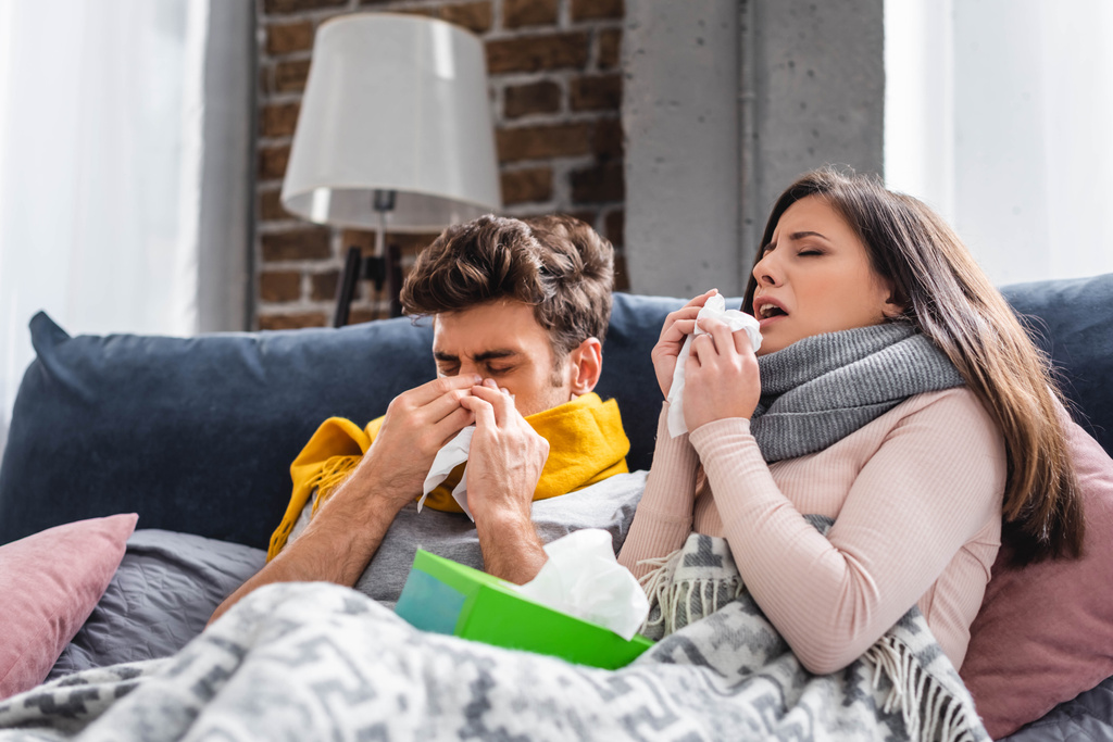 sick girlfriend and boyfriend sneezing and holding napkins in apartment  - Photo, Image