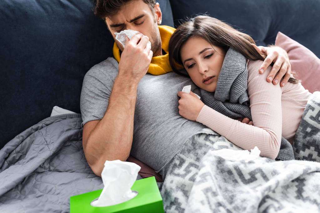 sick girlfriend and boyfriend sneezing and lying in bed  - Photo, Image