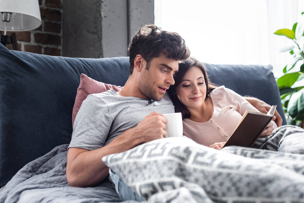 girlfriend reading book and boyfriend holding cup of tea  - Photo, Image