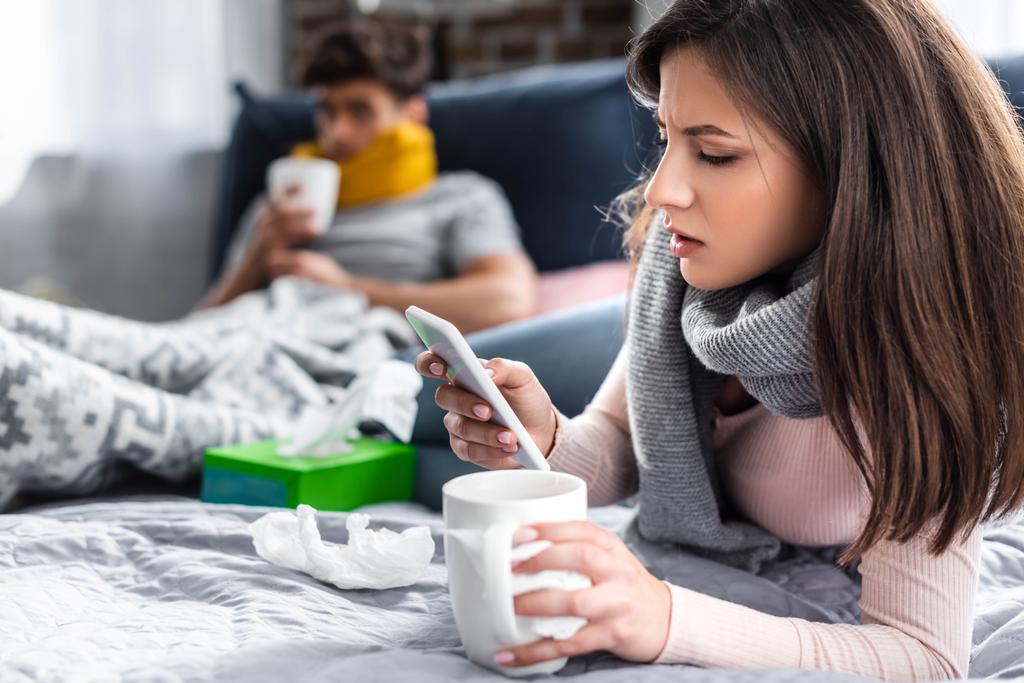 foyer sélectif de petite amie malade tenant tasse de thé et en utilisant smartphone
  - Photo, image