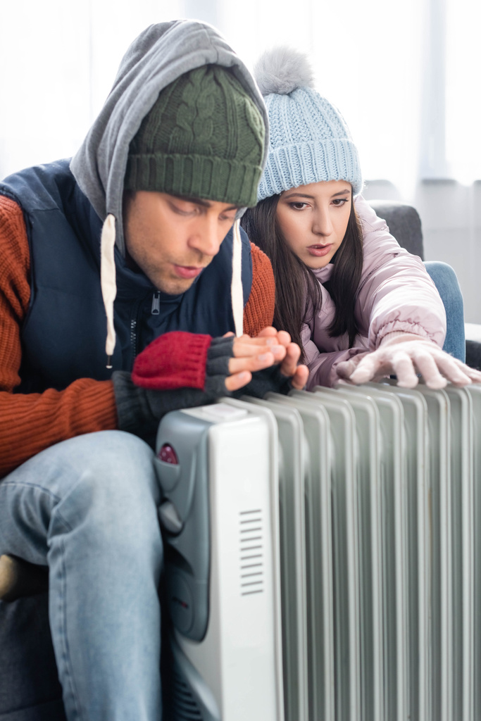 aantrekkelijke vriendin en vriend in de winter outfit opwarmen in de buurt verwarming  - Foto, afbeelding