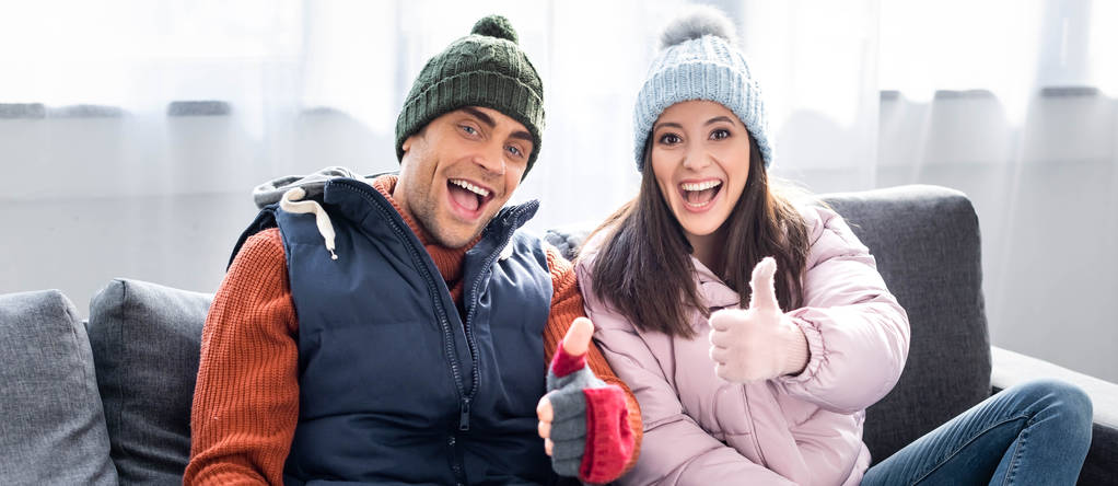 Kış kıyafetli kız ve erkek arkadaşın gülümseyip baş parmağını kaldırdığı panoramik bir fotoğraf.  - Fotoğraf, Görsel