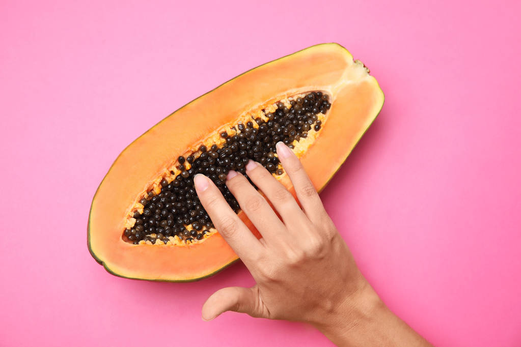Young woman touching half of papaya on pink background, top view. Sex concept - 写真・画像