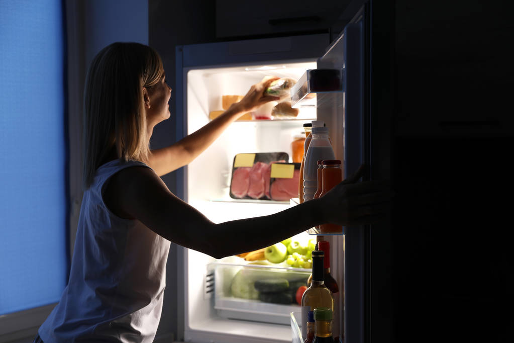 Femme sortant un sandwich du réfrigérateur dans la cuisine la nuit
 - Photo, image