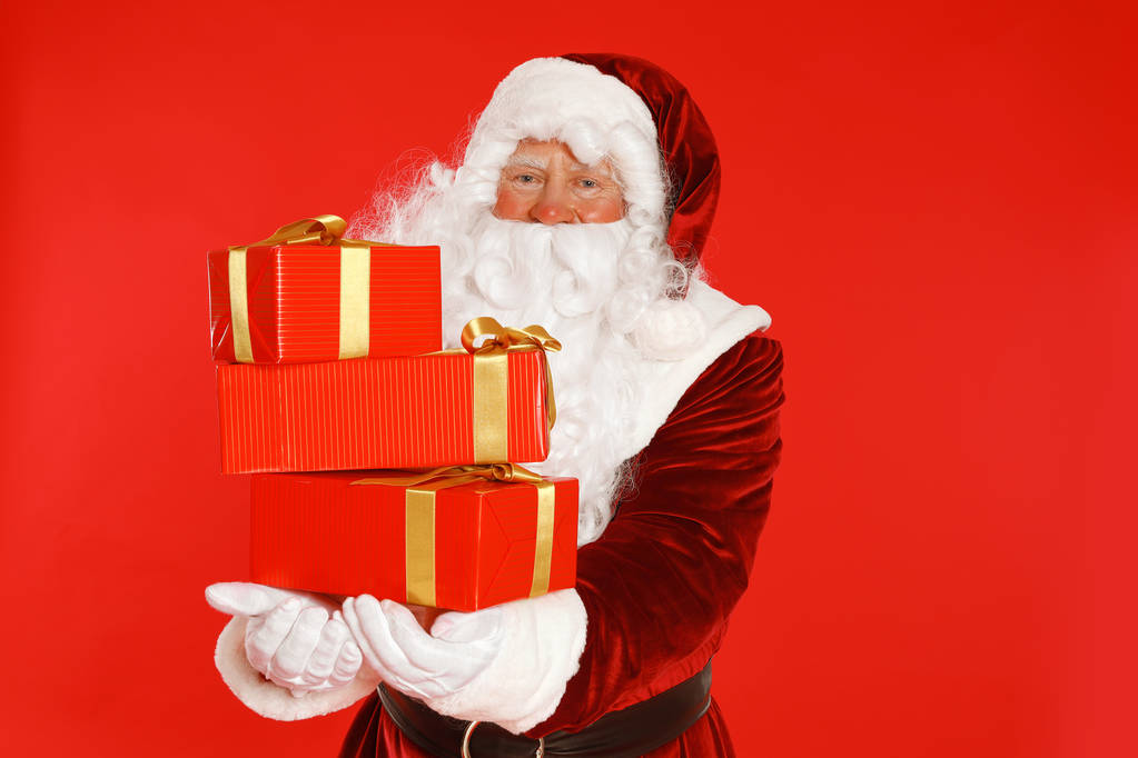 authentische Weihnachtsmann mit Geschenkschachteln auf rotem Hintergrund - Foto, Bild