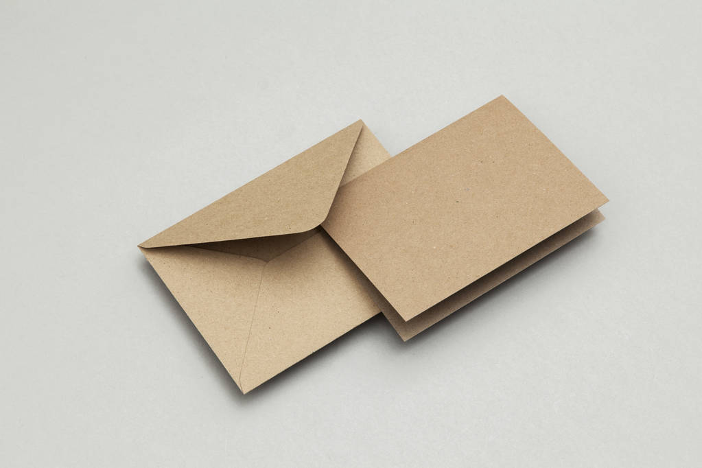 braune Kraftpapier-Blanko-Karte und Umschlag auf grauem Hintergrund - Foto, Bild