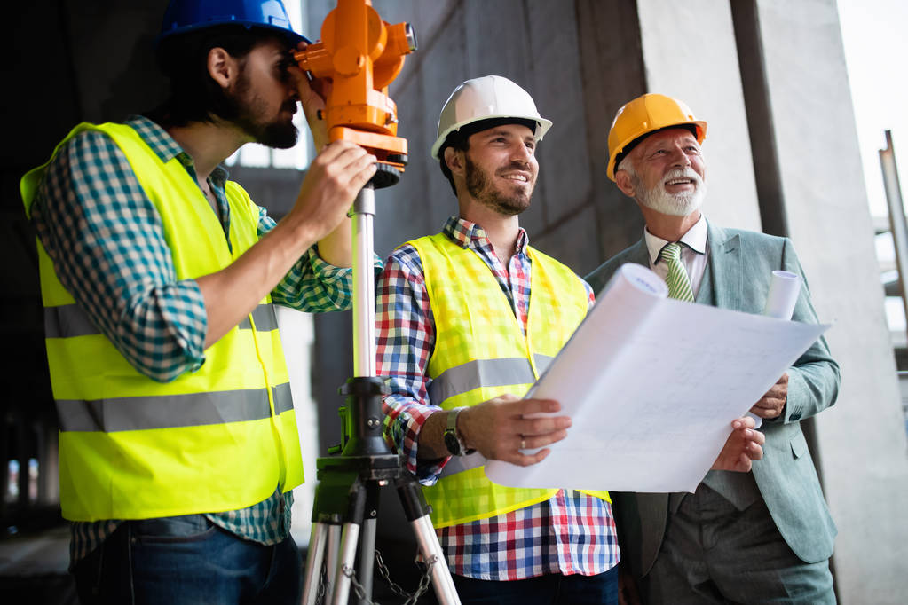 Уверенная команда архитекторов и инженеров, работающих вместе на строительной площадке
 - Фото, изображение