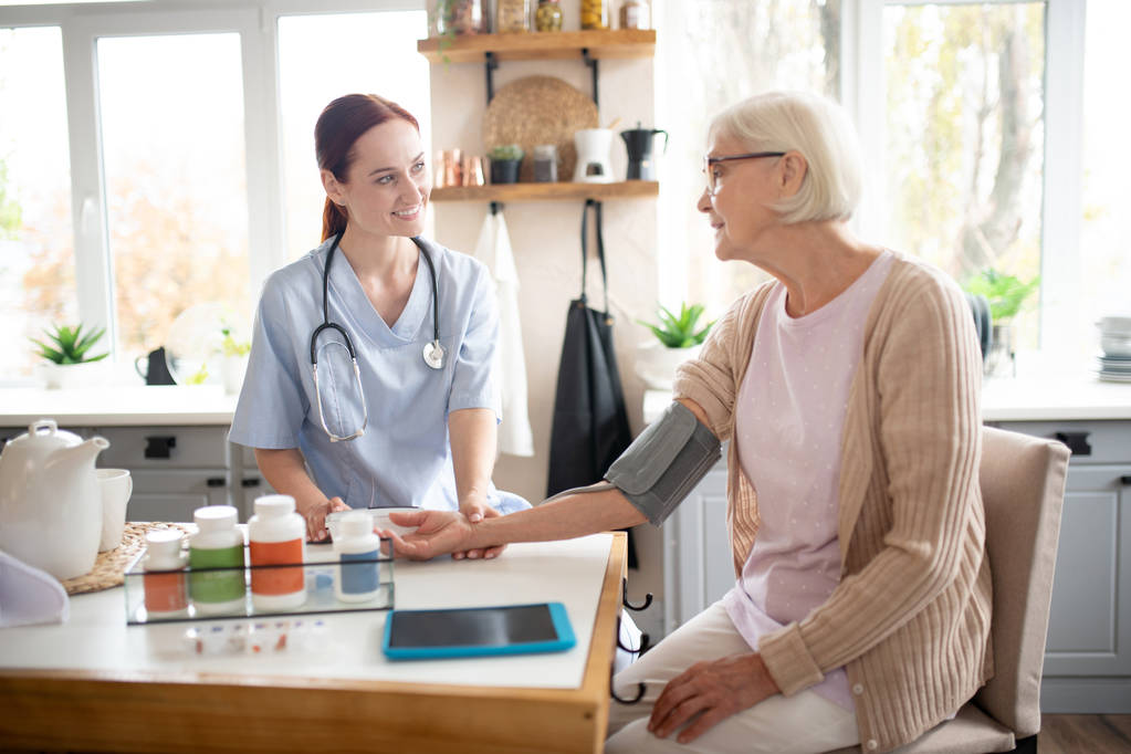 Rentner mit Brille spricht mit Krankenschwester - Foto, Bild