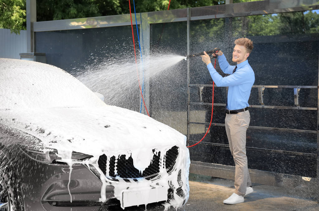 Üzletember takarítás Auto a nagynyomású vízsugár az önkiszolgáló autómosó - Fotó, kép