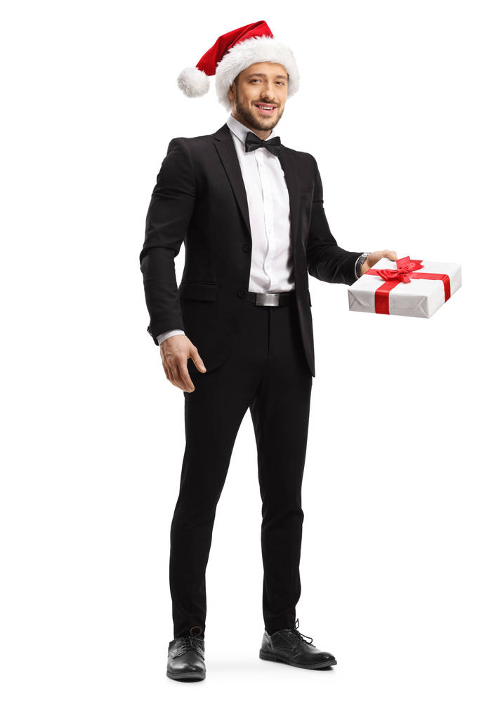 Młody elegancki mężczyzna w kapeluszu Świętego Mikołaja i trzymając prezent b - Zdjęcie, obraz