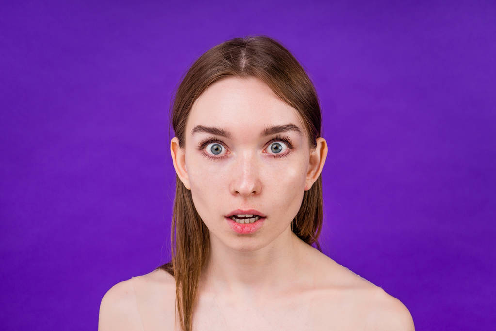 beautiful young woman with big ears and huge eyes on purple background in studio - Foto, afbeelding