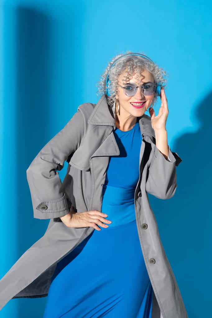 Mulher usando óculos e fones de ouvido posando perto de fundo
 - Foto, Imagem
