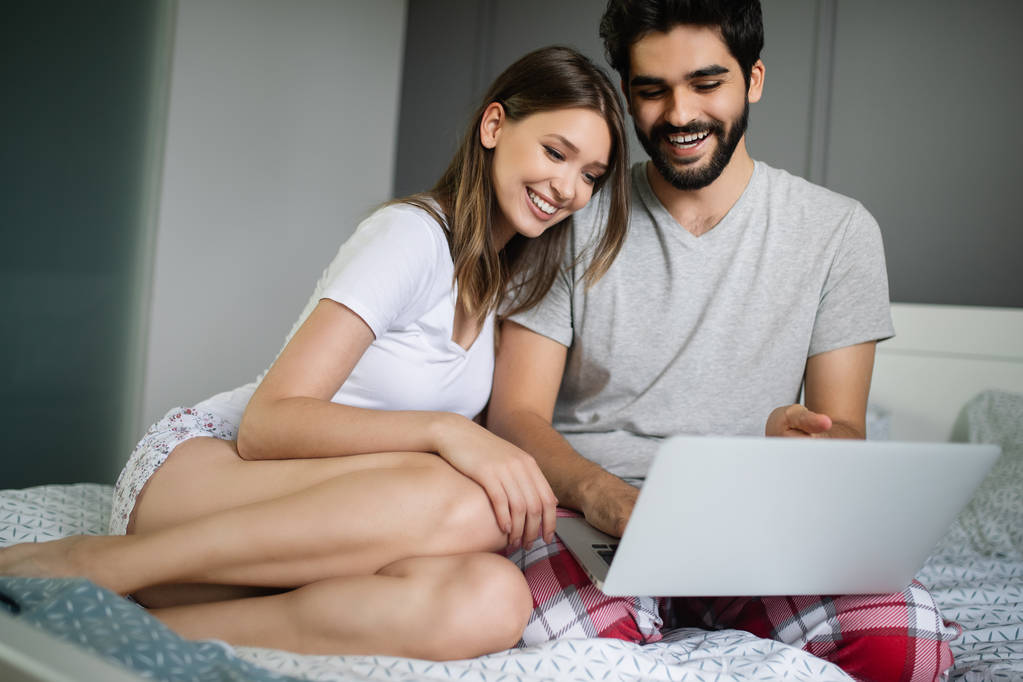 Νεαρό ζευγάρι που χαλαρώνει στο σπίτι με φορητό υπολογιστή. Αγάπη, ευτυχία, άνθρωποι και διασκέδαση έννοια. - Φωτογραφία, εικόνα