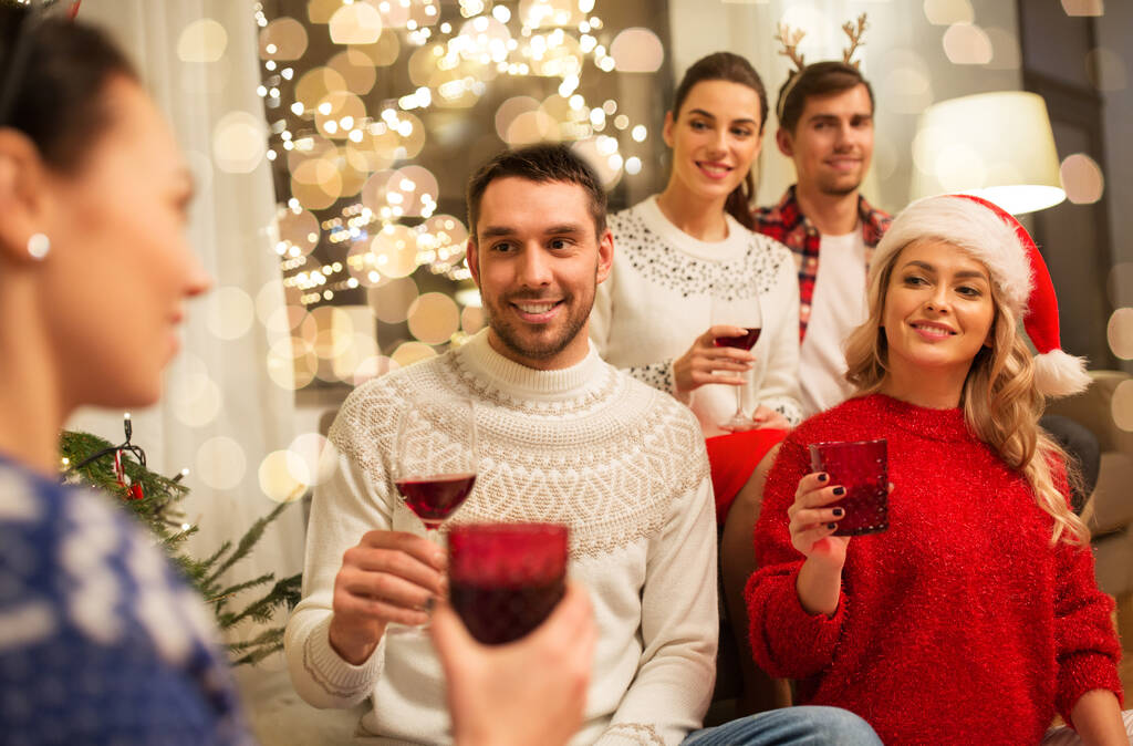 φίλοι γιορτάζουν τα Χριστούγεννα και πίνουν κρασί - Φωτογραφία, εικόνα