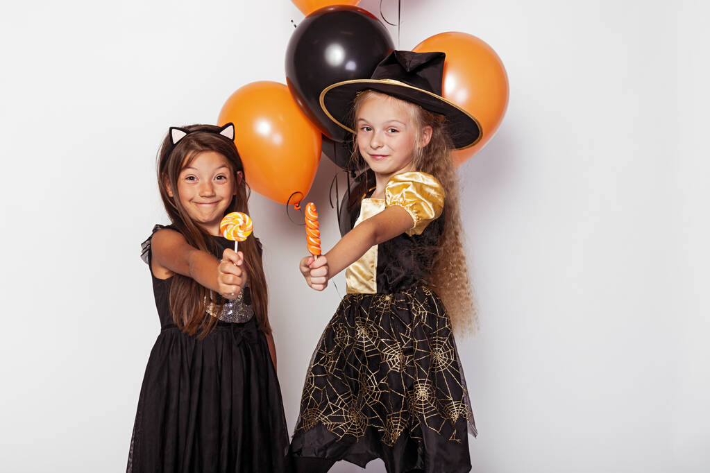 Niños en disfraces de Halloween mostrando piruletas de colores
 - Foto, imagen
