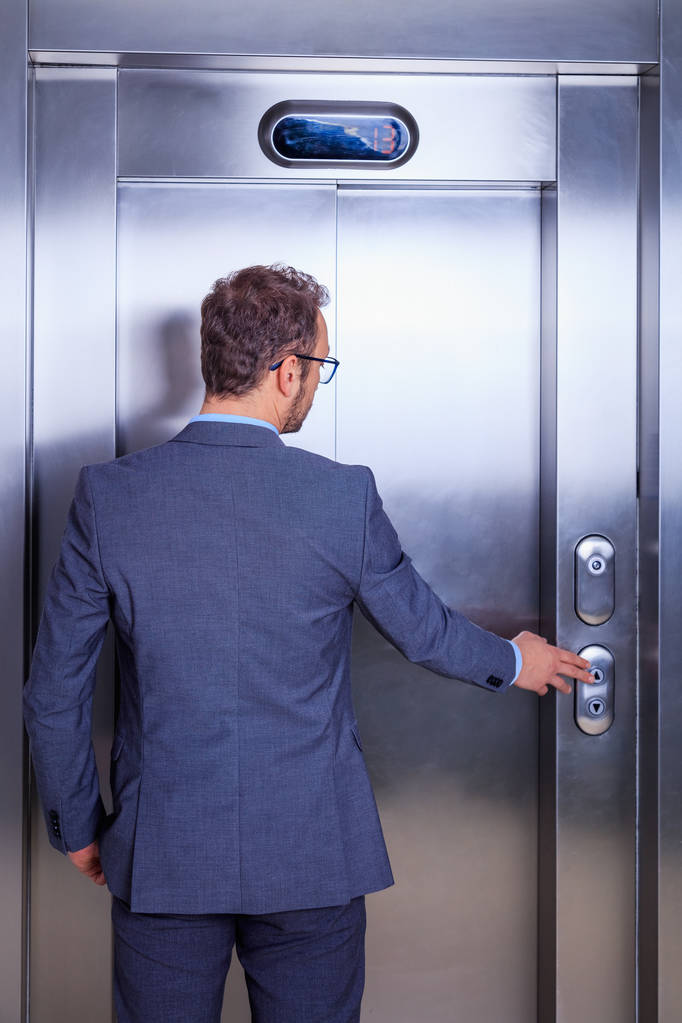 エレベーターの前で待っているスーツの若い専門家 - 写真・画像