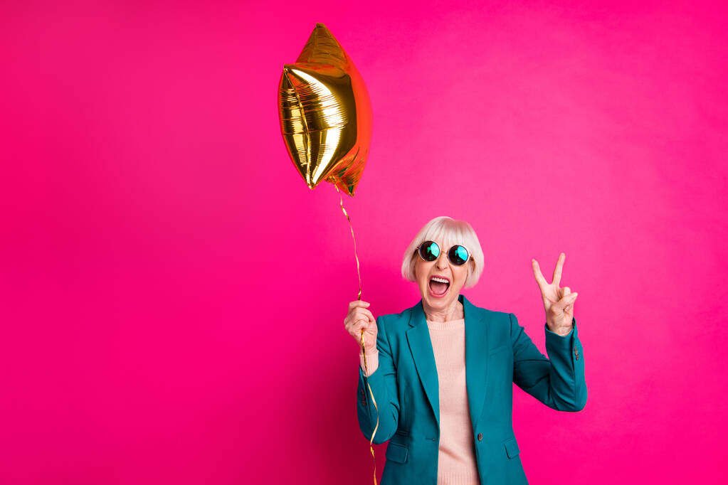 Portrait of her she nice-looking attractive crazy overjoyed cheerful cheery gray-haired lady holding balloon showing v-sign isolated on bright vivid shine vibrant pink fuchsia color background - Photo, Image