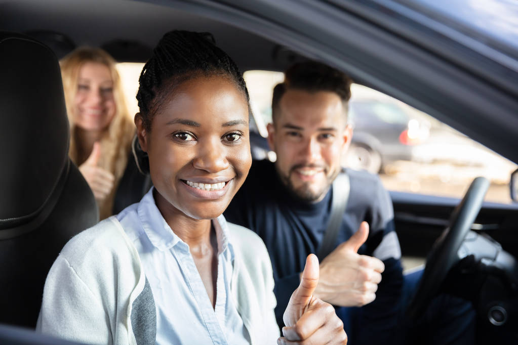 Πορτρέτο μιας Αφρικάνας που κάθεται στο αυτοκίνητο με τους φίλους της στο παρασκήνιο - Φωτογραφία, εικόνα