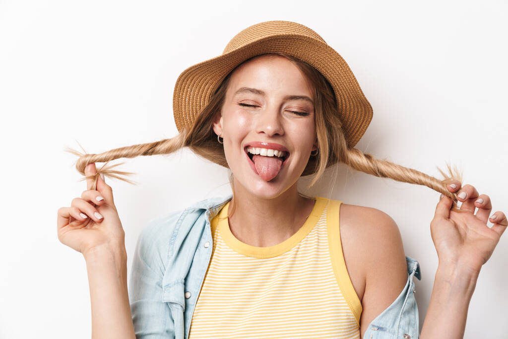 Happy souriant optimiste jeune jolie femme portant chapeau posant isolé sur fond de mur blanc
. - Photo, image