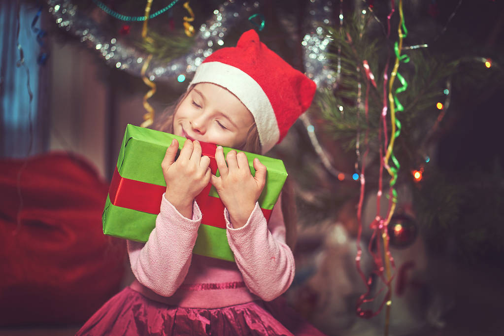 Kleine schattige baby met een cadeau in de buurt van de kerstboom. - Foto, afbeelding