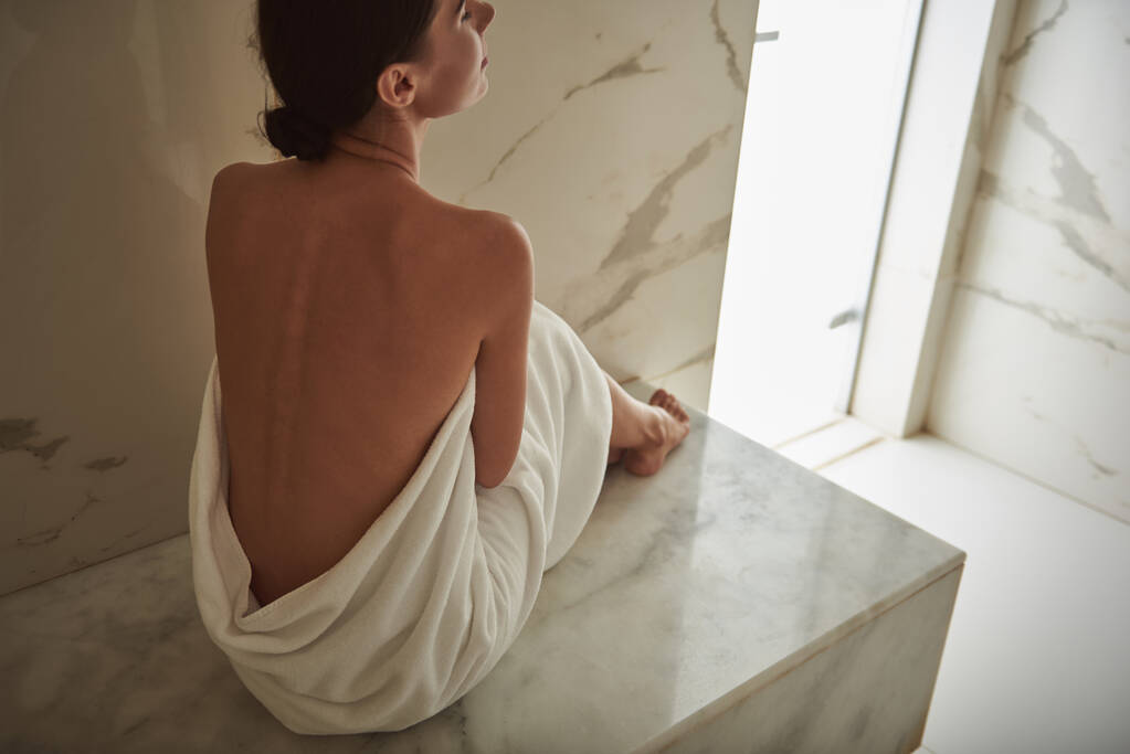 Bella parte posteriore della giovane donna rilassata coperta di asciugamano bianco
 - Foto, immagini