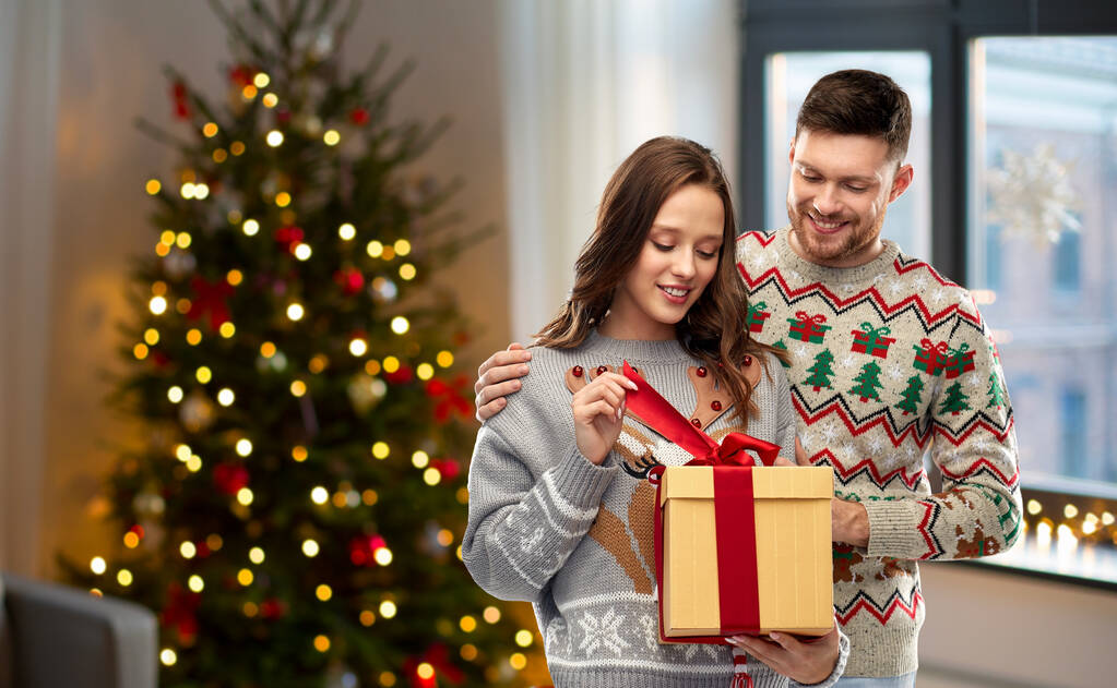 feliz pareja en suéteres de Navidad con caja de regalo - Foto, Imagen