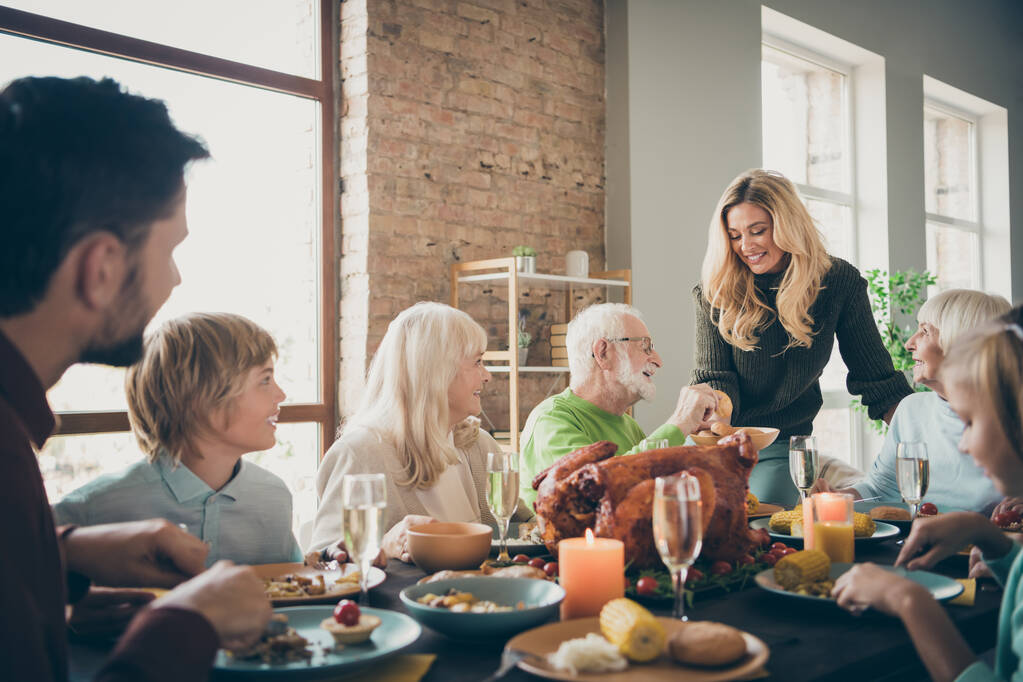 Fénykép a nagy családi összejövetel ül lakoma ételek vacsora asztal fiatal feleség ad régi szülők friss pékség több generációs az esti nappaliban beltérben - Fotó, kép