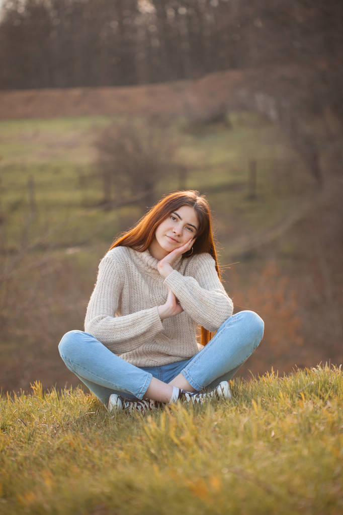 Gyönyörű fiatal nő ül a dombon ősszel - Fotó, kép