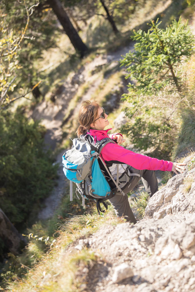 young  woman hiker climbing on rock on mountain peak cliff  - Photo, Image