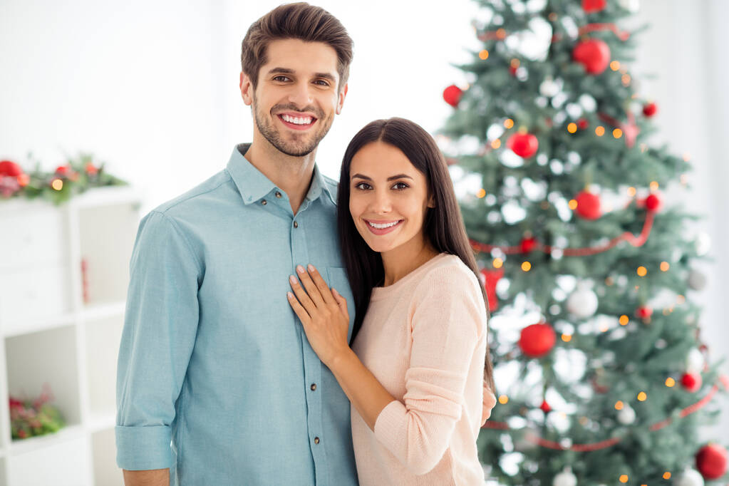クリスマスツリーの近くに2人の魅力的なロマンチックな恋人の抱擁の肖像屋内で家の中で夏の休日をお楽しみください - 写真・画像