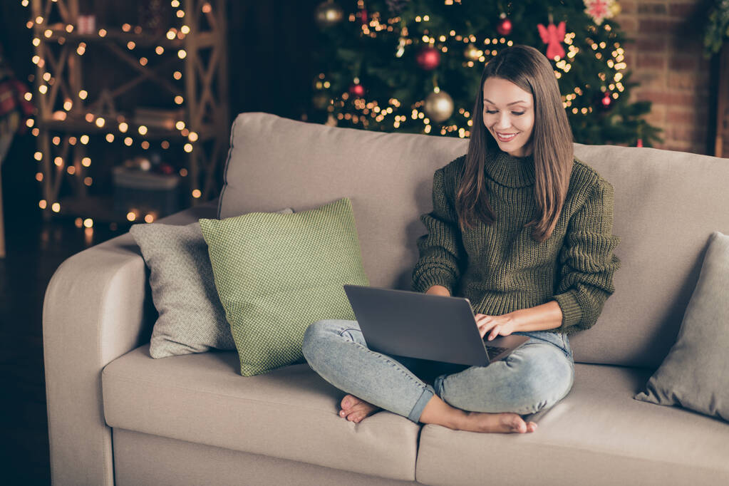 Felül magas szögből kilátás fotó pozitív lány viselni kötött jumper használata laptop keresés téli vásárlási kedvezmények szöveg ülni dívány keresztlábak házban tele karácsonyi dekoráció megvilágítás beltéri - Fotó, kép
