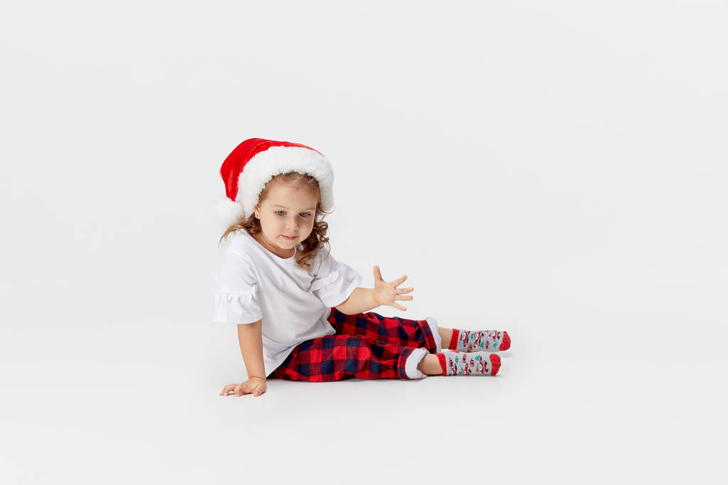 Porträt eines kleinen Mädchens mit Weihnachtsmannmütze, das isoliert auf weißem Hintergrund Spaß hat. Weihnachts- und Neujahrskonzept. - Foto, Bild