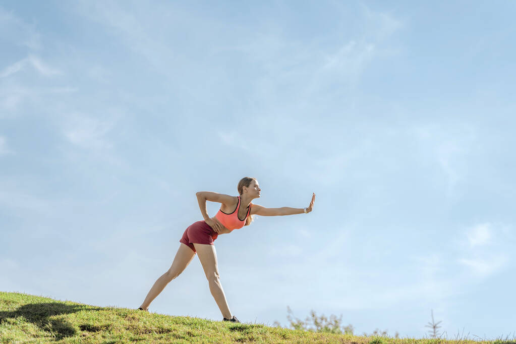 Lady doing gymnastics exercises on green hill - Photo, Image