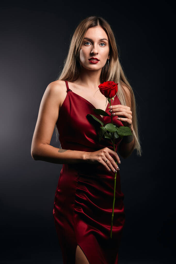sexy encantadora chica elegante en vestido de moda con una rosa en la mano posando a la cámara
 - Foto, imagen