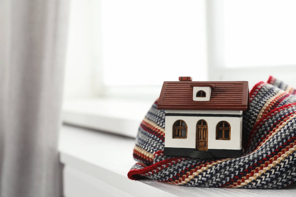 Modelo da casa e lenço no peitoril da janela dentro de casa, espaço para texto. Eficiência de aquecimento
 - Foto, Imagem