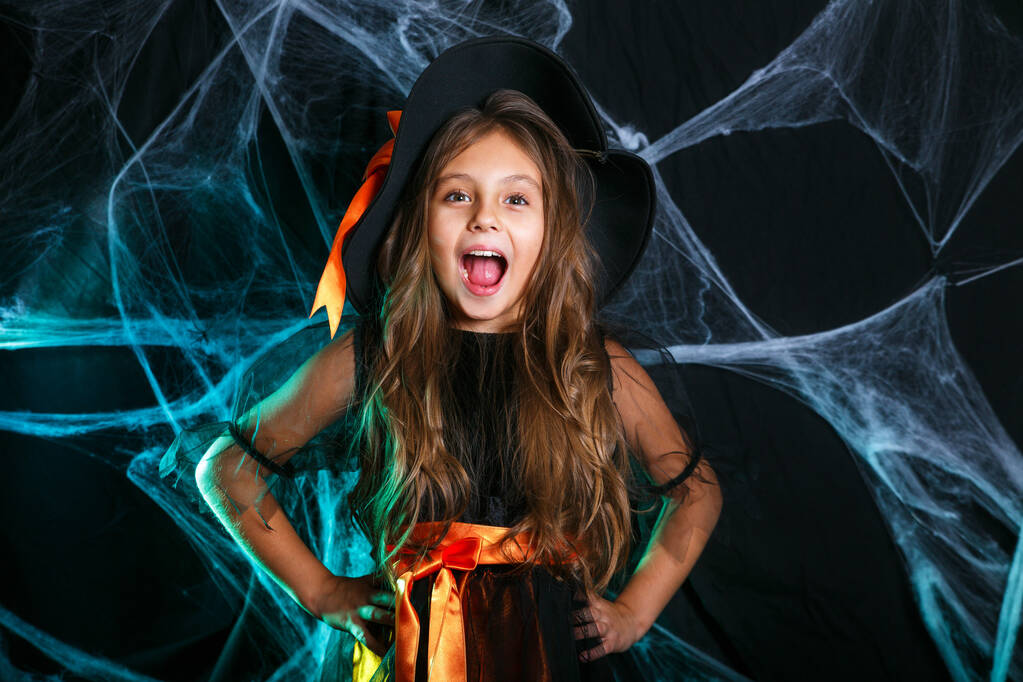 Concepto de bruja de Halloween: un niño brujo que se divierte sobre la tela de araña y con un fondo de calabazas curvas
. - Foto, imagen