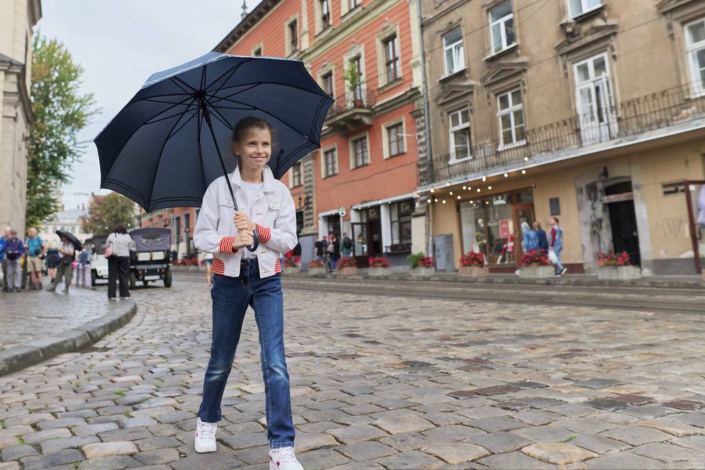 Criança menina andando com um guarda-chuva em uma rua da cidade
 - Foto, Imagem