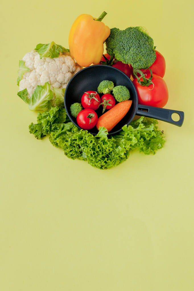 frisches Gemüse auf Pfanne auf gelbem Hintergrund. vegan und gesund - Foto, Bild