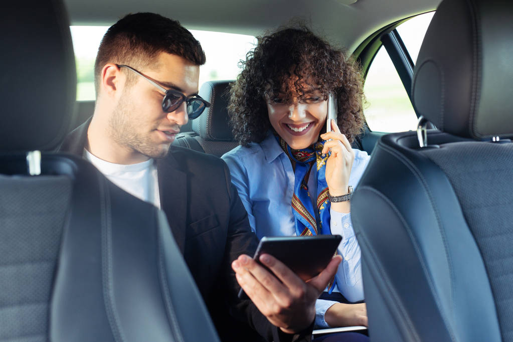 Biznesmen pokazując tablet do bizneswoman siedzi razem na samochodzie - Zdjęcie, obraz