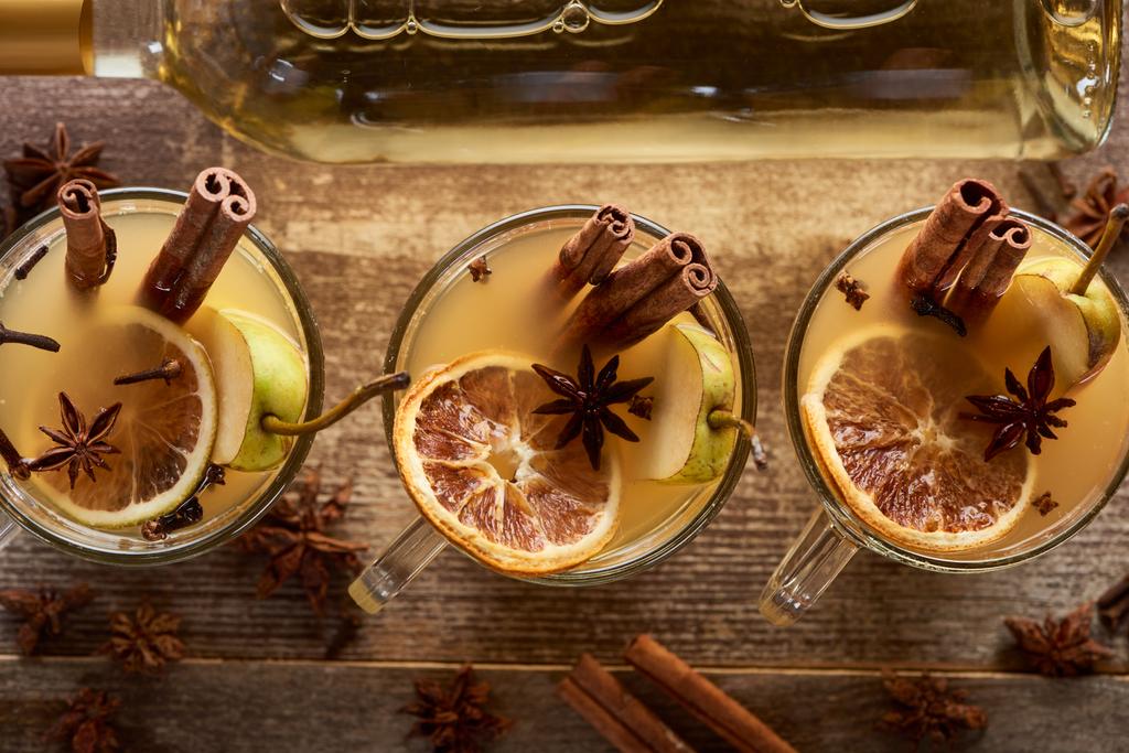 top view of seasonal pear mulled wine cocktails with spices and dried citrus on wooden rustic table - Photo, Image