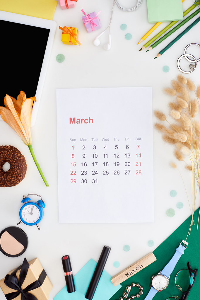 σελίδα ημερολογίου Μαρτίου, ψηφιακή ταμπλέτα, λουλούδι κρίνου, καρφιά, καλλυντικά, ντόνατ, μολύβια, κουτιά δώρων, ρολόι χειρός, ξυπνητήρι παιχνιδιών, μπλοκ με επιγραφή πορεία που απομονώνονται σε λευκό - Φωτογραφία, εικόνα