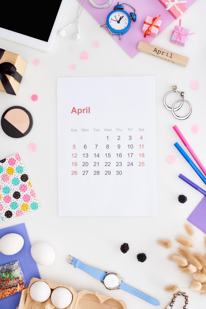 4月のカレンダーページ,デジタルタブレット,イースターの装飾,鶏の卵,化粧品,ブラックベリー,スパイクレット,腕時計,白い上に隔離された4月の碑文と木製のブロック - 写真・画像