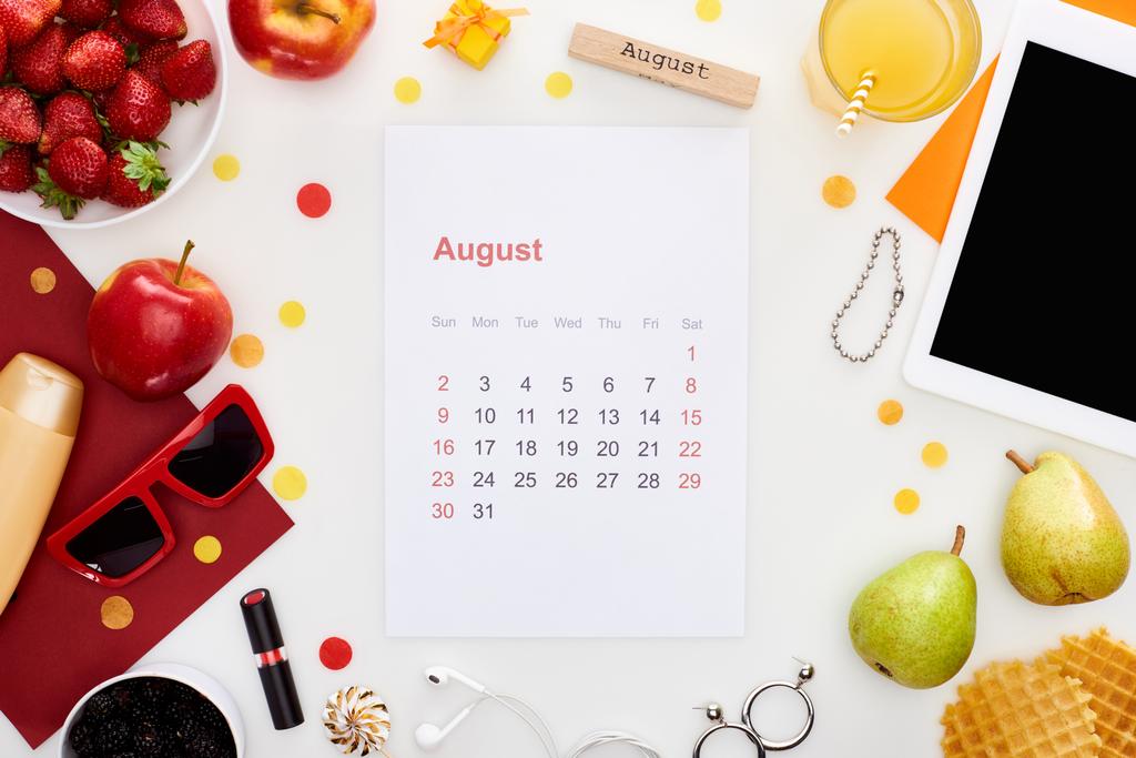 srpnový kalendář, dřevěný blok se vznešeným nápisem, digitální tablet, sluneční brýle, pomerančový džus, ovoce, vafle, kosmetika, sluchátka izolovaná na bílém - Fotografie, Obrázek