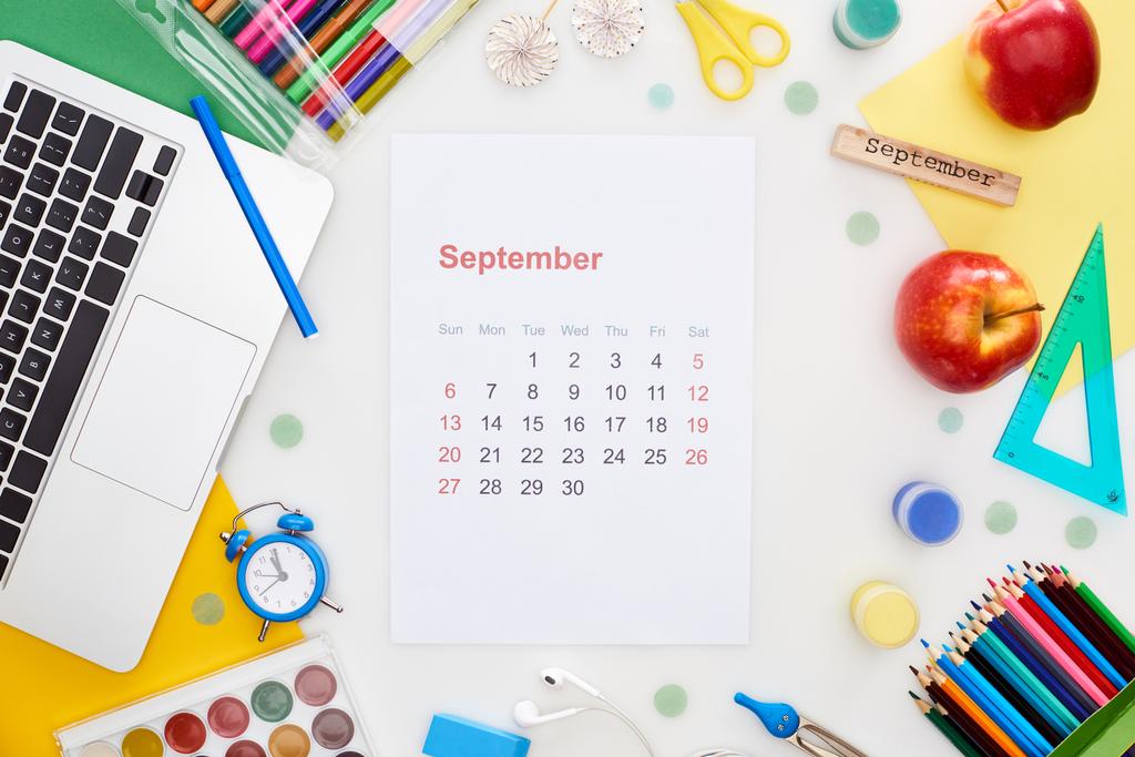 página de calendário setembro, laptop, maçãs, material escolar, papel multicolorido, bloco de madeira com inscrição setembro isolado em branco
  - Foto, Imagem