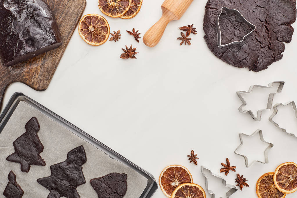 bovenaanzicht van rauw deeg voor chocolade Kerstkoekjes bij ingrediënten op witte achtergrond - Foto, afbeelding