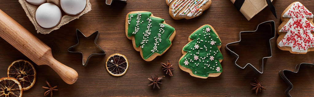 Noel ağacı kurabiyelerinin üst görüntüsü, hamur kalıpları, yumurtalar ve tahta masa üzerindeki merdane iğnesi, panoramik çekim - Fotoğraf, Görsel
