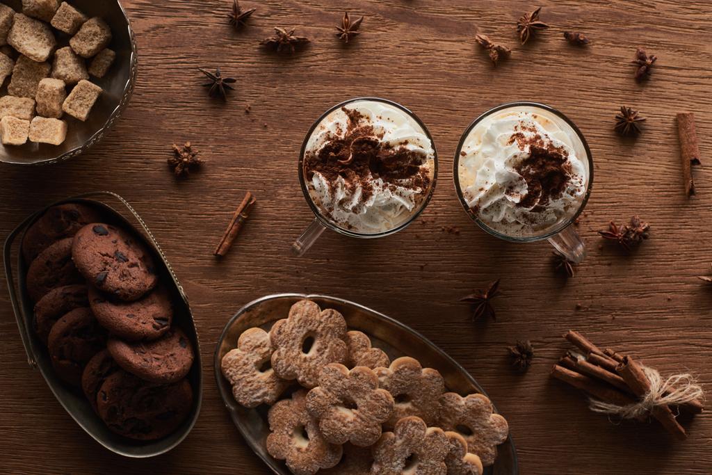 вид на рождественское какао возле печенья, аниса, корицы и коричневого сахара на деревянном столе
 - Фото, изображение
